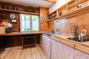 a kitchen with wooden walls and wooden counters and a window at Chata 'Leśne Kurki' in Kurki