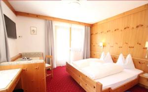 ein Hotelzimmer mit einem großen Bett und einem Schreibtisch in der Unterkunft Garni Olympia in Sulden