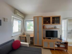 a living room with a couch and a tv at Apartment XENA Novi Vinodolski - Balcony and Sea View - first row to the sea - free wifi - free parking in Novi Vinodolski