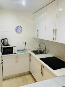 cocina blanca con fregadero y microondas en Casa Spencer, en Benidorm