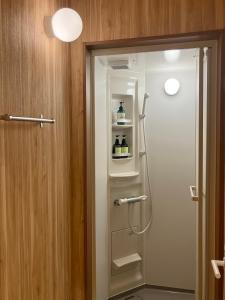 uma casa de banho com um chuveiro e uma porta de vidro em Guest House「さごんヴィレッジ」 em Tsushima