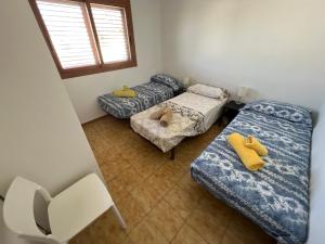 Zimmer mit 3 Betten, einem Stuhl und einem Fenster in der Unterkunft El Xalet d’en Joan Maria d’Altafulla in Altafulla