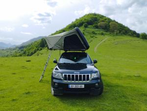 a car with a camper on the roof parked in a field at Rent4travel in Tbilisi City