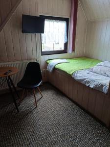 ein kleines Zimmer mit einem Bett, einem Stuhl und einem Fenster in der Unterkunft Pokoje Gościnne Grażyna Kozioł in Zakopane