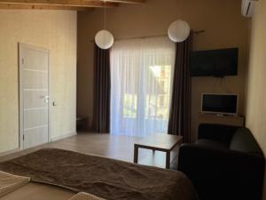 a bedroom with a bed and a couch and a window at Guest house LETTO in Gagra