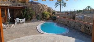 - une piscine dans un patio avec un mur en pierre dans l'établissement ANFI TOPAZ VILLA TAURO GOLF & BEACH 3 bedrooms 4 bathrooms private pool, à Mogán