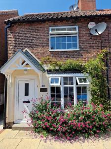 鲍特里Cosy Cottage Central Bawtry - 2 Bedroom - High End Furnishings的砖屋,有白色的门和一些花
