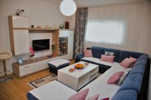 a living room with a blue couch and pink pillows at Apartman Flumen in Mostar