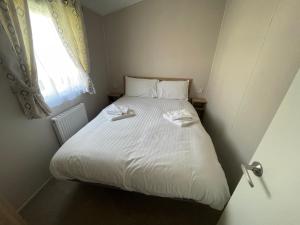 a small bedroom with a white bed with a window at Marine Holiday Park D & S rental A in Rhyl