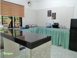 a kitchen with a table with a green counter top at Kampung Vibe @ Homestay Baiduri in Slim River