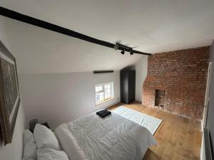 a bedroom with a white bed and a brick wall at Newtown Townhouse in Newtown