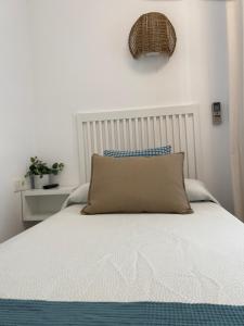 Una cama blanca con una almohada encima. en Hostal Andalucia, en Nerja