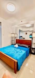 ein Schlafzimmer mit einem großen Bett mit einer blauen Decke in der Unterkunft De Luxe, Standard and Studio Suites -The Breeze Residences-close to Airport,Mall of Asia, US Embassy in Manila