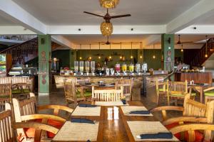 a restaurant with wooden tables and chairs and a bar at Nungwi Beach Resort by Turaco in Nungwi