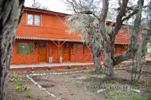 una casa naranja con un árbol delante de ella en Altos de Tolhuin en Tolhuin