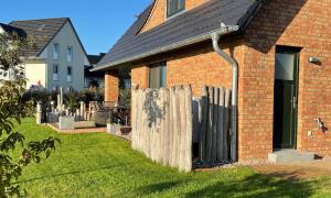 a brick house with a wooden fence in the yard at FH Kormoran in Ostseebad Karlshagen