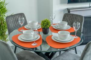 a glass table with plates and wine glasses on it at Spacious king size 1bed flat in leafy suburb in London