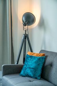 a lamp on a tripod next to a couch with a pillow at Spacious king size 1bed flat in leafy suburb in London