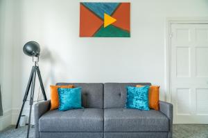 a living room with a gray couch with pillows and a painting at Spacious king size 1bed flat in leafy suburb in London