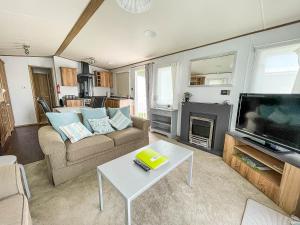 a living room with a couch and a tv and a table at Beautiful Caravan With Decking At Carlton Meres Holiday Park, Suffolk Ref 60022m in Saxmundham