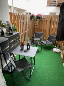 eine Terrasse mit grünem Teppich, Stühlen und einem Zaun in der Unterkunft Ferienwohnungen TalBach in Simmerath