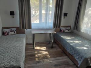 a room with two beds and a table and a window at Sweet villa Palanga in Palanga