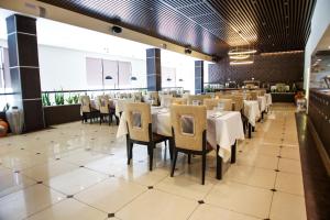 a dining room with white tables and chairs at Chagala Residence Atyrau in Atyraū