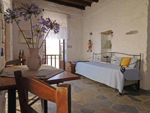 1 dormitorio con 1 cama, 1 mesa y 1 jarrón con flores en Philoxeno Traditional house - Ano Syros, en Ano Syros