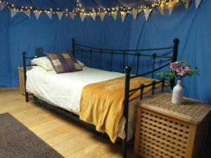 een slaapkamer met een bed en een blauwe muur met verlichting bij South Wales Yurt-Cosy, log burner & private garden 