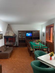 a living room with a table and chairs and a television at Villa prestigiosa ampie metrature in Altipiani di Arcinazzo