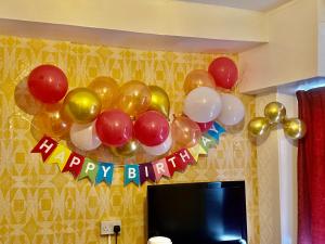 een hoop ballonnen en een happy birthday bord naast een tv bij Blackpool Central Hotel in Blackpool