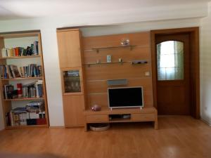 sala de estar con TV y estante de libros en Ferienhaus en Maria Wörth