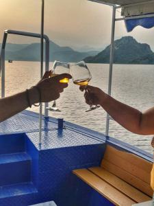 duas pessoas a segurar copos de vinho num barco em Skadar lake Apartments Pajovic em Virpazar