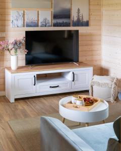 a living room with a large television and a table at Siedlisko Modrej Czapli. Domki na Kaszubach in Klonowo Dolne