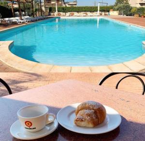 una taza de café y una pastelería en una mesa cerca de una piscina en Villaggio Magna Grecia, en Lazzaro