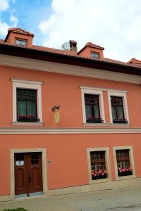 pomarańczowy budynek z oknami i kwiatami w obiekcie Ubytovanie u Janusa w Lewoczy
