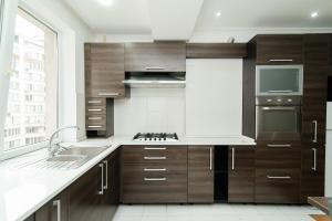 a kitchen with wooden cabinets and a large window at Elite Rentals Apartments in Chişinău