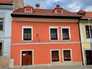 an orange building with flowers in the windows at Ubytovanie u Janusa in Levoča