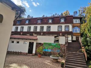 ein großes weißes Gebäude mit einer Treppe davor in der Unterkunft Waldhotel Pfarrmühle in Eisenberg