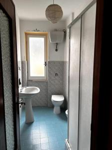 een badkamer met een wastafel, een toilet en een raam bij Flat with sea view and garden in Framura