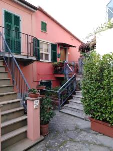 a pink building with stairs and plants in front of it at Flat with sea view and garden in Framura