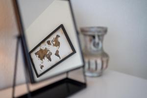 a framed picture of a map of the world next to a vase at Atlantic Selection - Vue panoramique sur l'océan avec Parking in Hendaye