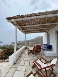 a patio with chairs and a wooden pergola at Salty Edge Holiday Home in Serifos Chora