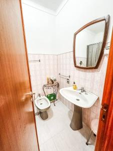 a bathroom with a sink and a toilet and a mirror at Casa da Mariazinha in Costa da Caparica