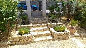 um jardim com uma parede de pedra e algumas plantas em La benvingude em Nyons