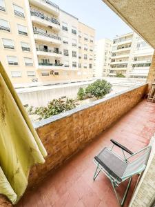 a chair on a balcony with a building at Casa da Mariazinha in Costa da Caparica