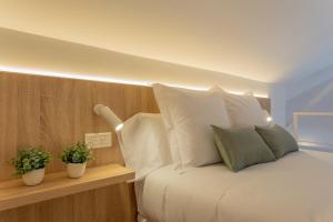 una camera da letto con letto, lenzuola e cuscini bianchi di Atico CL centro Granada a Granada