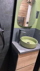 La salle de bains est pourvue d'un lavabo vert et d'un miroir. dans l'établissement Studio Dama neuf 4 p avec terrasse vue imprenable, à Montgenèvre