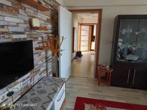 a living room with a brick wall and a flat screen tv at Rainfort apart Pınarkent 2+1 in Pamukkale