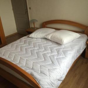 uma cama com lençóis brancos e almofadas em HOMESTAY LILLE em Lille